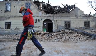 A rescuer walks past a building damaged in an earthquake in Petrinja, Croatia, Tuesday, Dec. 29, 2020. A strong earthquake has hit central Croatia and caused major damage and at least one death and some 20 injuries in the town southeast of the capital Zagreb. (AP Photo)