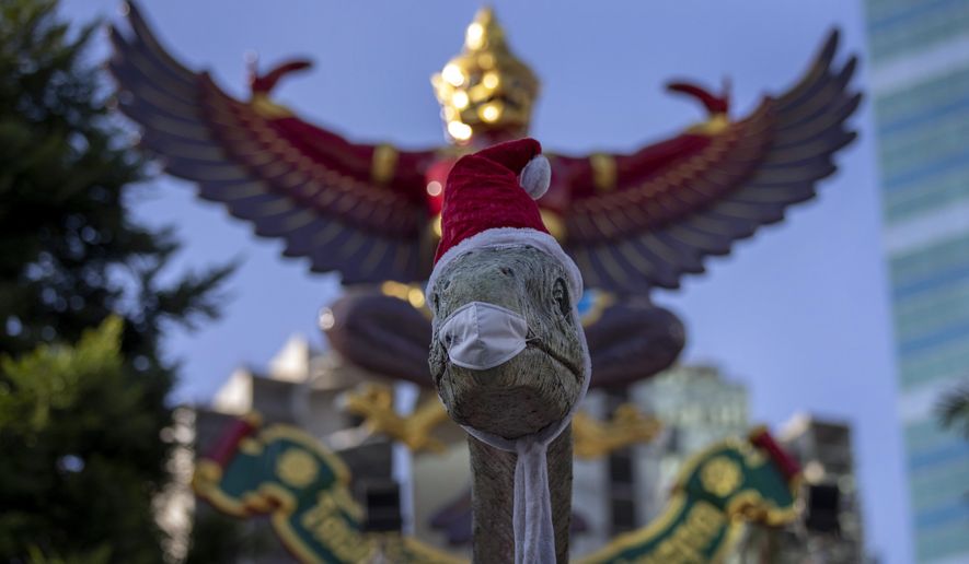 A sculpture of a dinosaurs is dressed with a Santa hat and a face mask in Bangkok, Thailand, Wednesday, Dec. 30, 2020. Officials in the Thai capital have announced new restrictions, including the closure of some entertainment facilities during the New Year&#39;s holiday, as infections continued to rise following a recent coronavirus outbreak. (AP Photo/Gemunu Amarasinghe)