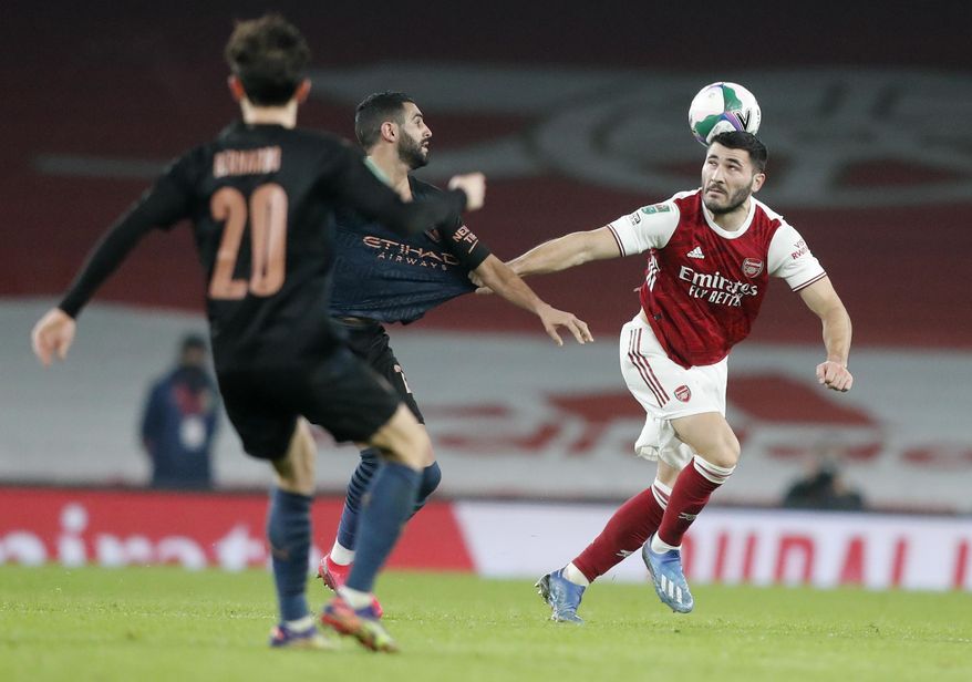 Arsenal's Sead Kolasinac, right, battles for the ball with Manchester City's Riyad Mahrez during the English League Cup quarterfinal soccer match between Arsenal and Manchester City at Emirates Stadium, London, Tuesday, Dec. 22, 2020. (AP Photo/Frank Augstein)