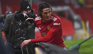 Manchester United&#x27;s Edinson Cavani gets up after running into the advertising boards during the English Premier League soccer match between Manchester Utd and Wolverhampton Wanderers at Old Trafford stadium in Manchester, England, Tuesday,Dec. 29, 2020. (Laurence Griffiths, Pool via AP)