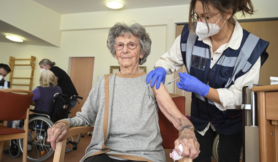 Medical student Mara Karcher vaccinates a resident Ella Holdenried of  Sankt Verena nursing home in Strassberg, Germany, Wednesday, Dec. 30, 2020. German authorities have reported more than 1,000 coronavirus-related deaths in one day for the first time since the pandemic began. The national disease control center, the Robert Koch Institute, said Wednesday that 1,129 more deaths were reported over the past 24 hours. (Felix Kaestle/dpa via AP)