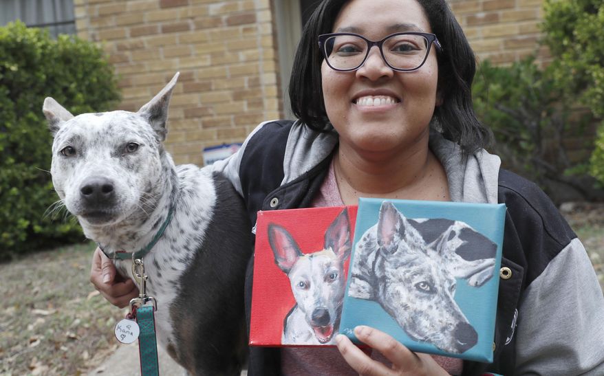 In this photo made Monday, March 2, 2020, Danielle Moore poses for photos with Kana and also paintings of the pet Australian cattle dog in Dallas. In the dog-eat-dog world of online shopping, Chewy has an unusual plan to fend off Amazon: turning pets into works of art. The online pet shop surprises customers with oil paintings of their furry friends, a move the company says wins them customers for life. (AP Photo/LM Otero)
