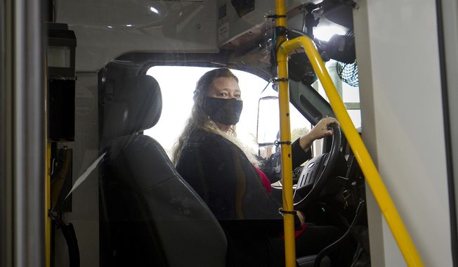Benzie County bus driver Sandi Saxton wears some of the protective gear bus drivers are using to help prevent the spread of COVID-19 in Beulah, Mich., Wednesday, Dec. 23, 2020. You&#x27;ll get where you need to be but locals know the extra miles Benzie Bus&#x27; drivers are willing to to. They might pick up a small neighborhood&#x27;s worth of food bank supplies, or take a quick detour to college a regular&#x27;s waiting prescription. (Jan-Michael Stump/Traverse City Record-Eagle via AP)