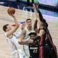 Dallas Mavericks guard Luka Doncic, left, shoots over Miami Heat&#x27;s Tyler Herro (14) and Bam Adebayo, obscured, as Miami&#x27;s Jimmy Butler (22) and Dallas&#x27; Dwight Powell watch during the first half of an NBA basketball game Friday, Jan. 1, 2021, in Dallas. (AP Photo/Jeffrey McWhorter)