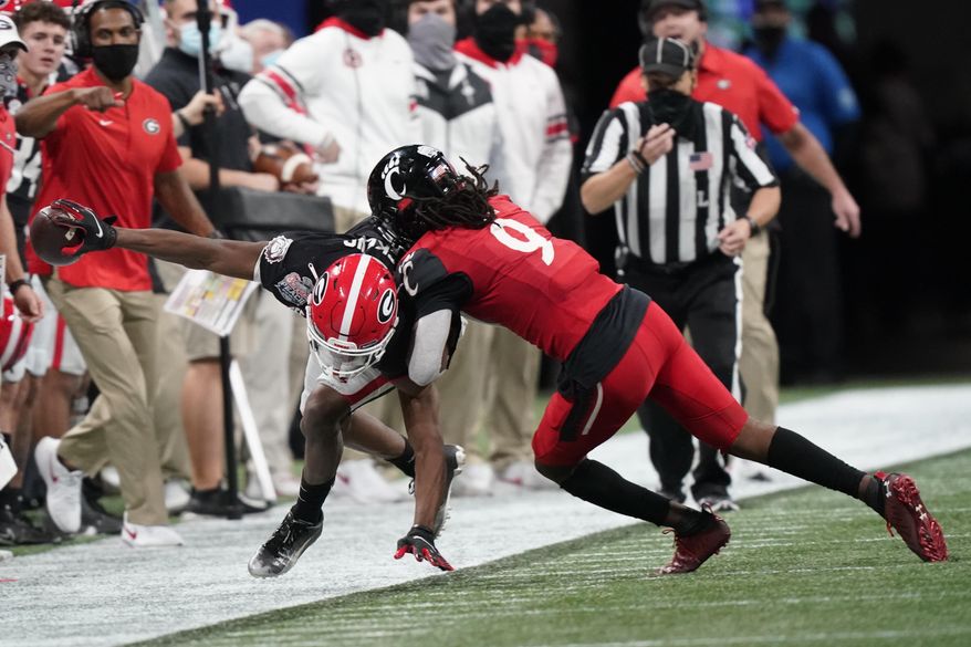 Georgia wide receiver George Pickens (1) is hit by Cincinnati cornerback Arquon Bush (9) during the second half of the Peach Bowl NCAA college football game, Friday, Jan. 1, 2021, in Atlanta. (AP Photo/Brynn Anderson)