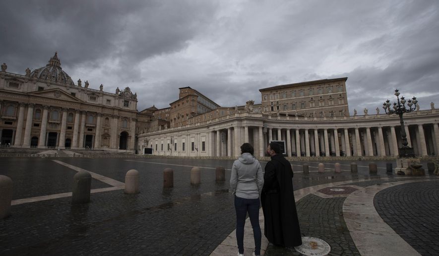 Two people stand in an empty St.Peter's Square, at the Vatican, as Pope Francis recites the Angelus noon prayer in his studio Friday, Jan. 1, 2021. (AP Photo/Alessandra Tarantino)