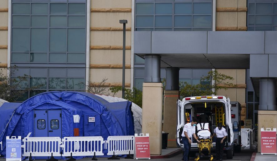 FILE - In this Dec. 17, 2020, file photo, medical workers remove a stretcher from an ambulance near medical tents outside the emergency room at UCI Medical Center, in Irvine, Calif. After months spent tamping down surges and keeping the coronavirus at manageable levels, a variety of factors combined to bring California to a crisis point in the pandemic. (AP Photo/Ashley Landis, File)