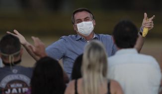 FILE - in this July 24, 2020 file photo, Brazil&#39;s President Jair Bolsonaro, who is infected with COVID-19, wears a protective face mask as he talks with supporters during a Brazilian flag retreat ceremony outside his official residence the Alvorada Palace, in Brasilia, Brazil. The South American nation proud of its role as a regional leader in science, technology and medicine, finds itself falling behind its neighbors in the global race for immunization against a pandemic that has already killed nearly 200,000 of its people. (AP Photo/Eraldo Peres, File)