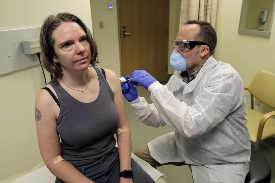 FILE - In this March 16, 2020 file photo, a pharmacist gives Jennifer Haller, left, the first shot in the first-stage safety study clinical trial of a potential vaccine for COVID-19, the disease caused by the new coronavirus, at the Kaiser Permanente Washington Health Research Institute in Seattle. Tens of thousands of Americans have volunteered to test COVID-19 vaccines, but only about half of them got the real thing. Now, with the first vaccine rollouts and a surge in coronavirus infections, experts are debating what to do about the half that got a dummy shot. (AP Photo/Ted S. Warren, File)