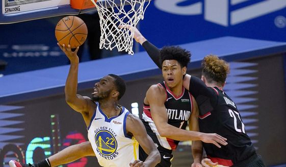 Golden State Warriors forward Andrew Wiggins (22) drives to the basket between Portland Trail Blazers guard Anfernee Simons (1) and center Jusuf Nurkic (27) during the first half of an NBA basketball game in San Francisco, Friday, Jan. 1, 2021. (AP Photo/Tony Avelar)