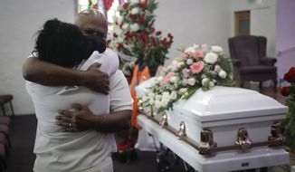 FILE - In this July 21, 2020, file photo, Darryl Hutchinson, facing camera, is hugged by a relative during a funeral service for Lydia Nunez, who was Hutchinson&#39;s cousin at the Metropolitan Baptist Church in Los Angeles. Nunez died from COVID-19. Southern California funeral homes are turning away bereaved families because they&#39;re running out of space for the bodies piling up during an unrelenting coronavirus surge. (AP Photo/Marcio Jose Sanchez, File)