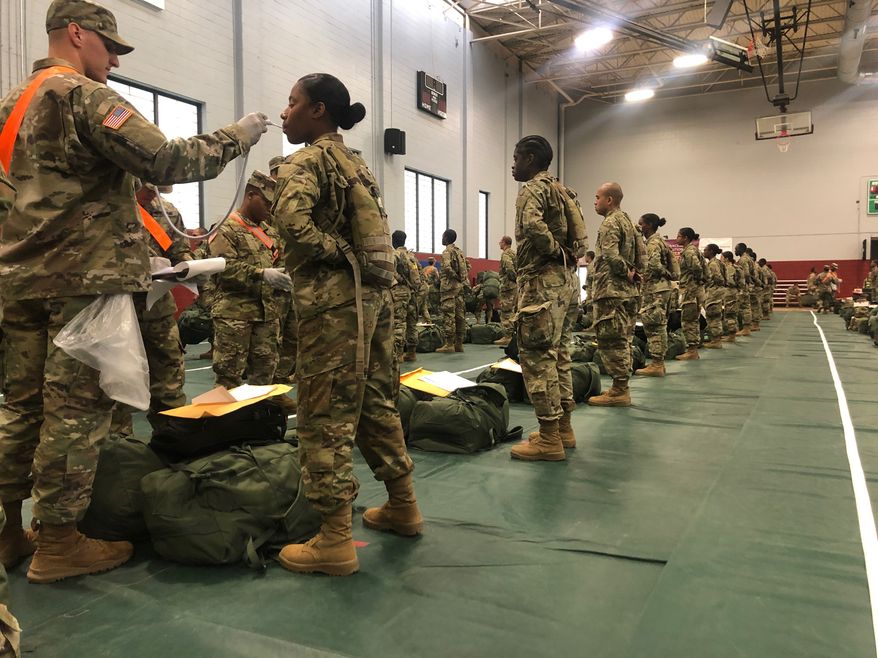 In this image provided by the U.S. Army, recent Army basic combat training graduates have their temperatures taken as they arrive at Fort Lee, Va, on March 31, 2020, after being transported using sterilized buses from Fort Jackson, S.C. (U.S. Army via AP)