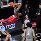 Washington Wizards center Thomas Bryant (13) hangs from the rim after dunking over Brooklyn Nets center Jarrett Allen (31) and Nets guard Timothe Luwawu-Cabarrot (9) during the fourth quarter of an NBA basketball game against the Brooklyn Nets, Sunday, Jan. 3, 2021, in New York. (AP Photo/Kathy Willens)