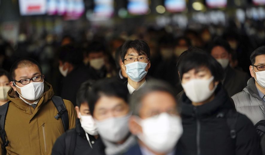 Some people commute on the first business day of the year at a train station Monday, Jan. 4, 2021, in Tokyo. Japanese Prime Minister Yoshihide Suga said Monday vaccine approval was being speeded up and border controls beefed up to curb the spread of the coronavirus, and he promised to consider declaring a state of emergency.(AP Photo/Eugene Hoshiko)