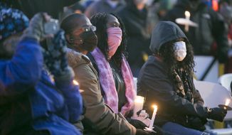 Toscha Flowers, center in pink scarf, the fiance of slain Rockford bowler Jerome Woodfork, sits in the front row and listens to speakers during a vigil at Don Carter Lanes for the six victims of a shooting that occurred there, Saturday, Jan. 2, 2021 in Rockford, Ill. (Scott P. Yates/Rockford Register Star via AP)
