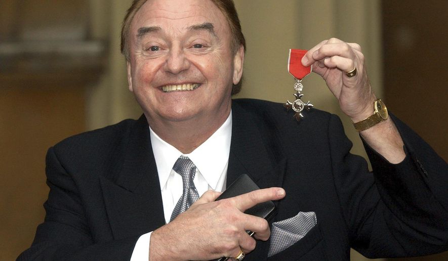 FILE - In this Dec. 12, 2003 file photo, Gerry Marsden holds his MBE. Gerry Marsden, the British singer and lead singer of Gerry and the Pacemakers, who was instrumental in turning a song from the Rodgers and Hammerstein musical “Carousel” into one of the great anthems in the world of football, has died. He was 78. (Matthew Fearn/PA via AP, File)