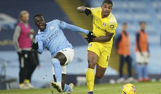 Manchester City&#39;s Benjamin Mendy, left, challenges for the ball with Fulham&#39;s Mario Lemina during an English Premier League soccer match between Manchester City and Fulham at the Etihad stadium in Manchester, England, Saturday, Dec. 5, 2020. (AP Photo/Dave Thompson)