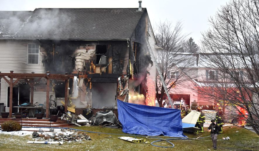 First responders investigate the scene of a plane that crashed into or near a house, setting the house on fire, on Dakota Dr. between Grispen Rd. and Cedar Mill Dr. in Lyon Twp. near the Oakland Southwest Airport, Saturday night, Jan. 2, 2021. (Todd McInturf/Detroit News via AP)