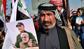 Supporters of the Popular Mobilization Forces hold posters of Abu Mahdi al-Muhandis, deputy commander of the Popular Mobilization Forces, front, and General Qassem Soleimani, head of Iran&#39;s Quds force during a protest, in Tahrir Square, Iraq, Sunday, Jan. 3, 2021. Thousands of Iraqis converged on a landmark central square in Baghdad on Sunday to commemorate the anniversary of the killing of Soleimanil and al-Muhandis in a U.S. drone strike. (AP Photo/Khalid Mohammed)