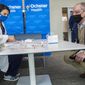 Louisiana Governor John Bel Edwards, right, talks with Dr. Mona Moghareh, a pharmacist with Ochsner Medical Center in Jefferson, La., as she sets up a station to administer the first vials of the coronavirus vaccine on Monday, Dec. 14, 2020. (Chris Granger/The Advocate via AP)