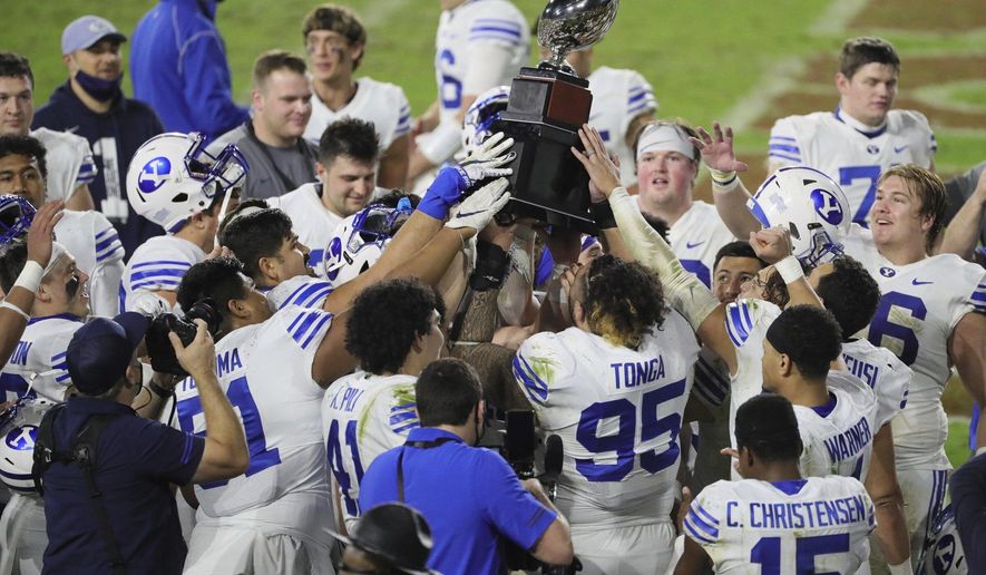 BYU players hold the championship trophy after defeating UCF in the Boca Raton Bowl NCAA college football game at FAU Stadium in Boca Raton, Fla. Tuesday, Dec. 22, 2020.(Al Diaz/Miami Herald via AP)