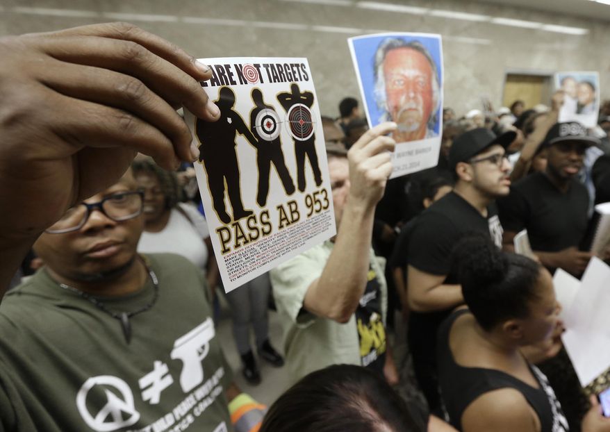 FILE - In this Sept. 2, 2015 file photo protestors shouting "Black Lives Matter" hold up photos of people they claim are the victims of police violence as they block the hallway outside the governor's office while successfully demanding the passage of AB953, in Sacramento, Calif. The state's Racial and Identity Profiling Advisory (RIPA) Board said in its 2021 fourth annual report that people who were perceived as Black were more than twice as likely to be stopped as their percentage of the population would suggest. (AP Photo/Rich Pedroncelli, File)