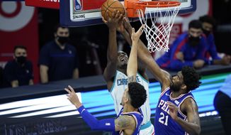 Charlotte Hornets&#39; Bismack Biyombo, left, goes up for a shot against Philadelphia 76ers&#39; Joel Embiid, right, and Danny Green during the second half of an NBA basketball game, Monday, Jan. 4, 2021, in Philadelphia. (AP Photo/Matt Slocum)