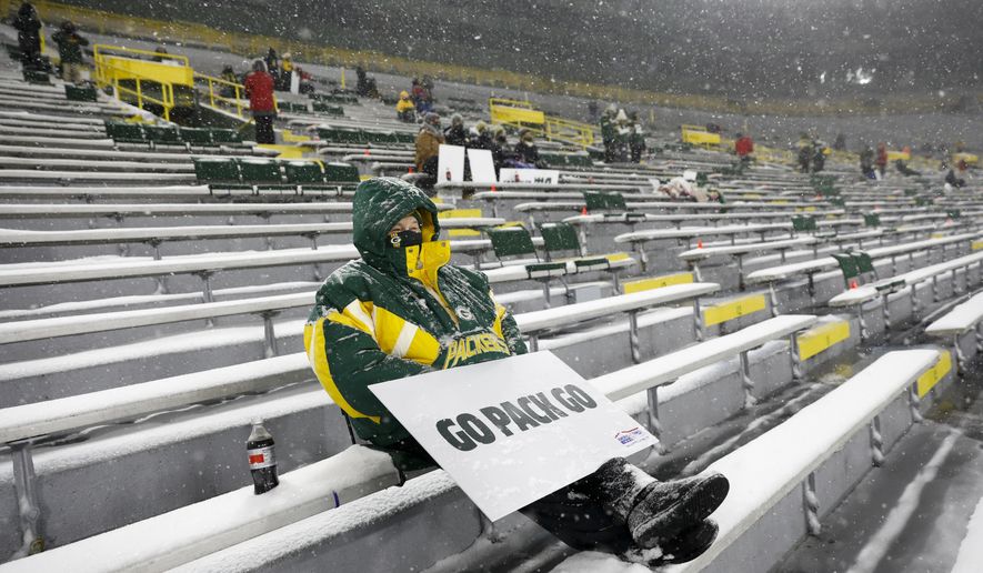 A few fans watch in Lambeau Field during the first half of an NFL football game between the Green Bay Packers and the Tennessee Titans in Green Bay, Wis., in this Sunday, Dec. 27, 2020, file photo. The eight teams hosting NFL playoff games this month are more than happy to be staying home with all of comfort it brings, but the actual advantage of playing there all but disappeared during this pandemic season of mostly empty stadiums. (AP Photo/Mike Roemer, File) **FILE**