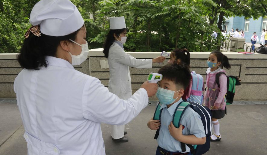 In this June 3, 2020, file photo, Kim Song Ju Primary school students have their temperatures checked before entering the school in Pyongyang, North Korea. North Korea, which has a broken medical infrastructure and deep poverty, has taken some of the world’s toughest anti-virus measures and claims to be coronavirus-free, an assertion widely disputed by foreign experts. (AP Photo/Jon Chol Jin, File)