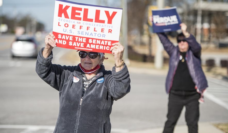 Jean Calvert, left, and Debbie Epling wave signs for their favorite candidates at the intersection Belair and Washington Roads during Georgia's U.S. Senate runoff election in Evans, Ga., Tuesday morning, Jan. 5, 2021. Republican Sen. Kelly Loeffler and David Perdue are being challenged by Democrats Jon Ossoff and Raphael Warnock in Tuesday's runoff. (Michael Holahan/The Augusta Chronicle via AP)