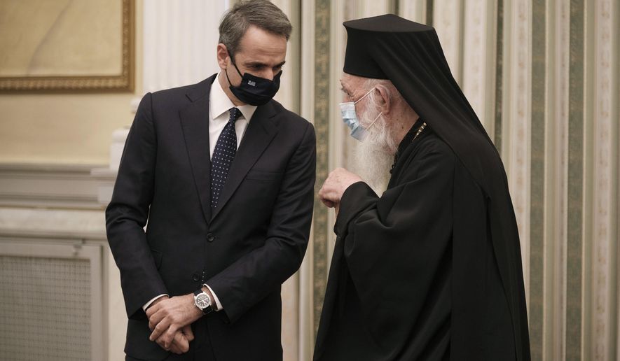 In this photo provided by the Greek Prime Minister's Office, Greece's Prime Minister Kyriakos Mitsotakis, left, talks with Archbishop of Athens and All Greece Ieronimos during a swearing-in ceremony of the new cabinet at the Presidential Palace in Athens, Tuesday, Jan. 5, 2021. Greece's powerful Orthodox Church is rebelling against a government order to briefly close places of worship under a weeklong drive to tighten virus restrictions before the planned reopening of schools. The conservative Church's ruling body issued a statement Monday directing priests to admit worshippers during indoor services for Wednesday's feast of the Epiphany. (Dimitris Papamitsos/Greek Prime Minister's Office via AP)