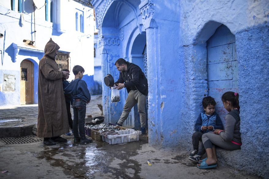 A fishermen sells his catch of the day in an alleyway in Chefchaouen, in northern Morocco, Saturday, Dec. 26, 2020. Known as the Blue Pearl of Morocco, the photogenic and mountainous town is usually overcrowded with tourists, but has been deserted this year due to the Covid-19 pandemic. (AP Photo/Mosa'ab Elshamy)