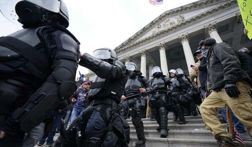 Police in riot gear walk out of the Capitol, Wednesday, Jan. 6, 2021, in Washington. As Congress prepares to affirm President-elect Joe Biden's victory, thousands of people have gathered to show their support for President Donald Trump and his claims of election fraud. (AP Photo/Manuel Balce Ceneta)