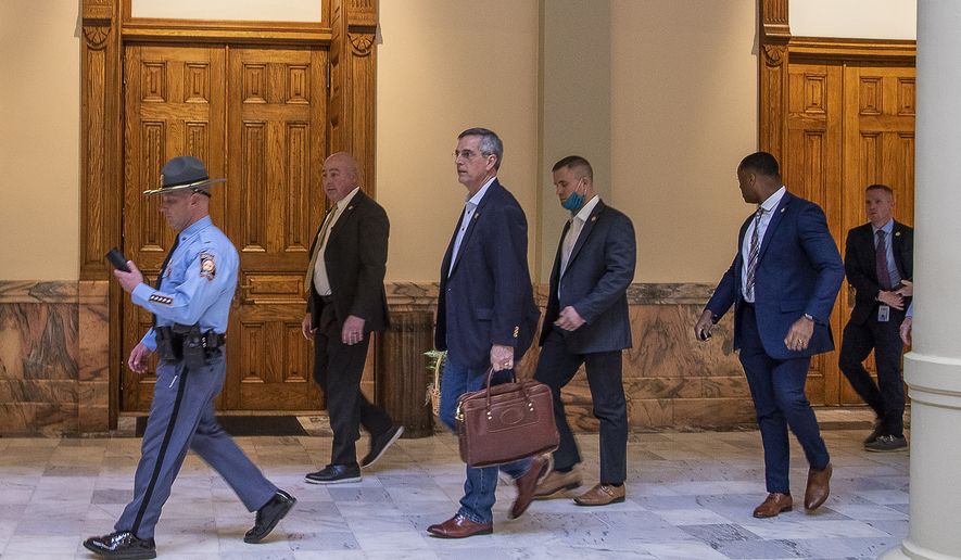 Lead by a Georgia State Trooper, Georgia Secretary of State Brad Raffensperger, center, exits the Georgia State Capitol building after hearing reports of threats, Wednesday, Jan. 6, 2021, in Atlanta. (Alyssa Pointer/Atlanta Journal-Constitution via AP)