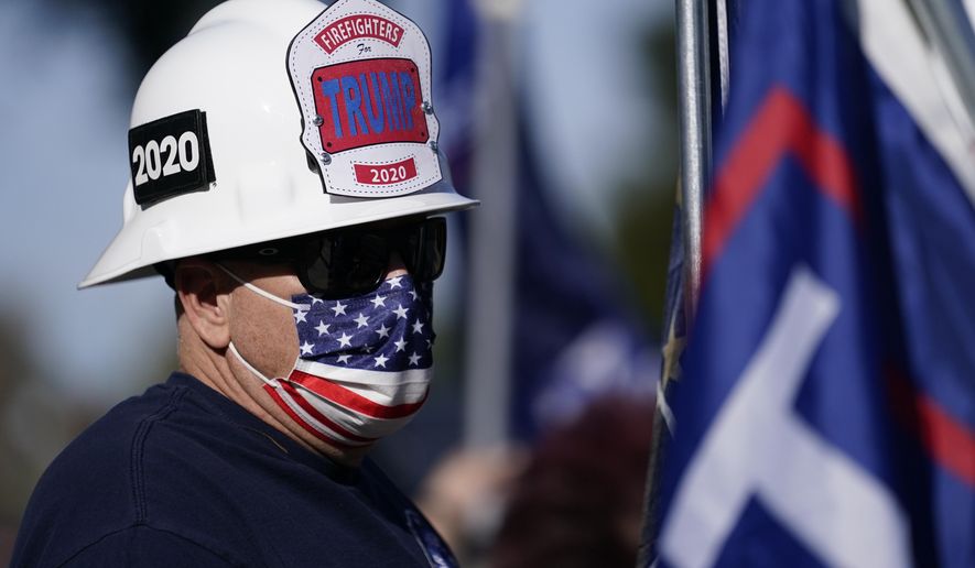 A man wearing a firefighter's helmet attends a rally in support of President Donald Trump outside Thousand Oaks City Hall Wednesday, Jan. 6, 2021, in Thousand Oaks, Calif. (AP Photo/Ashley Landis)