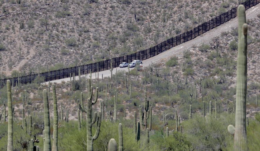 In this Aug. 22, 2019, file photo, U.S. Customs and Patrol agents sit along a section of the international border wall that runs through Organ Pipe National Monument in Lukeville, Ariz. A public-private project that maps the bodies of border crossers recovered from Arizona&#39;s inhospitable deserts, valleys and mountains said as of Monday, Jan. 4, 2021, that it documented 227 such deaths in 2020, the highest in a decade following the hottest, driest summer in state history. (AP Photo/Matt York, File)