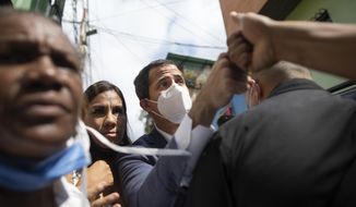 Venezuelan opposition leader Juan Guaidó fist bumps with a resident during a visit to La Lucha neighborhood of Caracas, Venezuela, Thursday, Dec. 10, 2020. Guaidó’s coalition is holding a referendum which culminates on Saturday. It asks Venezuelans at home and abroad to say whether they wish to end President Nicolas Maduro’s rule and hold fresh presidential and legislative elections. (AP Photo/Ariana Cubillos)