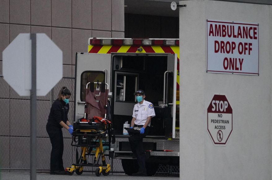 Emergency medical technicians sanitize an ambulance strecher after transporting a patient at Los Angeles County + USC Medical Center in Los Angeles, Tuesday, Jan. 5, 2021. Los Angeles continues to see hospitalizations rise day after day, setting a new record Tuesday with almost 8,000 hospitalized and more than a fifth of those in intensive care units. (AP Photo/Damian Dovarganes)