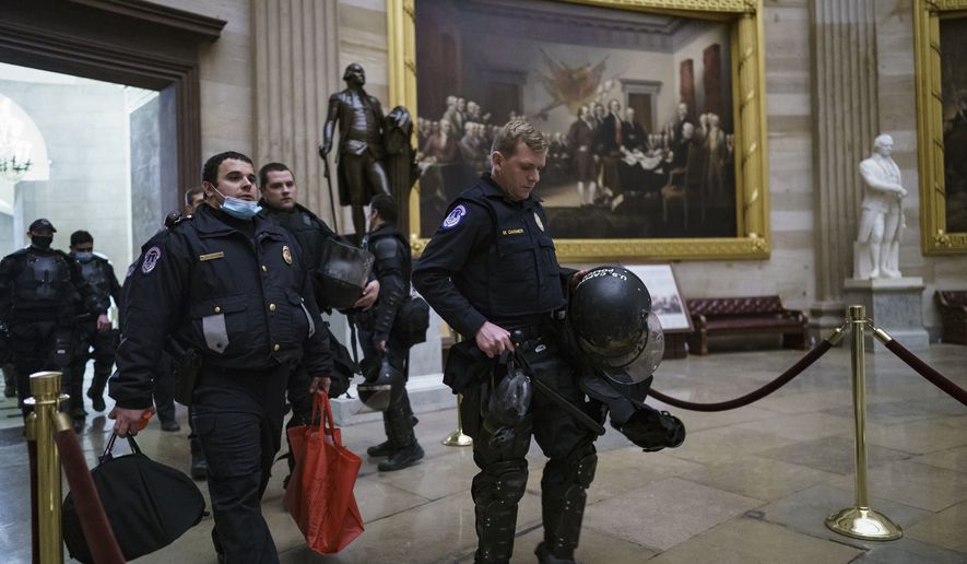 U.S. Capitol Police officers walk through the Rotunda as they and other federal police forces responded as violent protesters loyal to President Donald Trump stormed the U.S. Capitol today, at the Capitol in Washington, Wednesday, Jan. 6, 2021. (AP Photo/J. Scott Applewhite)
