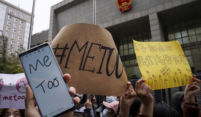 Supporters hold banners as they wait for of Zhou Xiaoxuan outside at a courthouse where Zhou is appearing in a sexual harassment case in Beijing on Wednesday, Dec. 2, 2020. In a blow to the MeToo movement in China, a court in Zhejiang province found a young man and woman guilty of defamation against a prominent Chinese journalist on Tuesday, Jan. 5, 2021 for publishing an alleged account of sexual harassment. (AP Photo/Andy Wong)