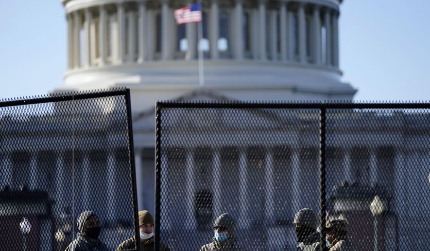 With the U.S. Capitol in the background, members of the National Guard stand behind newly placed fencing around the Capitol grounds the day after violent protesters loyal to President Donald Trump stormed the U.S. Congress in Washington, Thursday, Jan. 7, 2021. (AP Photo/Evan Vucci)