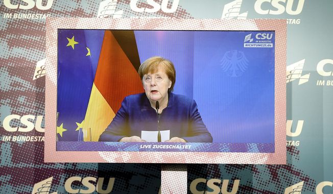 German Chancellor Angela Merkel is seen on a screen, making a statement on the events in Washington with the storming of the Capitol by Trump supporters at the beginning of the digital press conference at the winter retreat of the CSU parliamentary group in the Bundestag, Berlin, Germany, Thursday, Jan. 7, 2021. (Kay Nietfeld/Pool via AP)