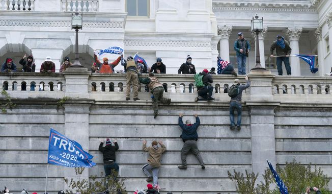 Supporters of President Donald Trump climb the west wall of the the U.S. Capitol on Wednesday, Jan. 6, 2021, in Washington. (AP Photo/Jose Luis Magana)