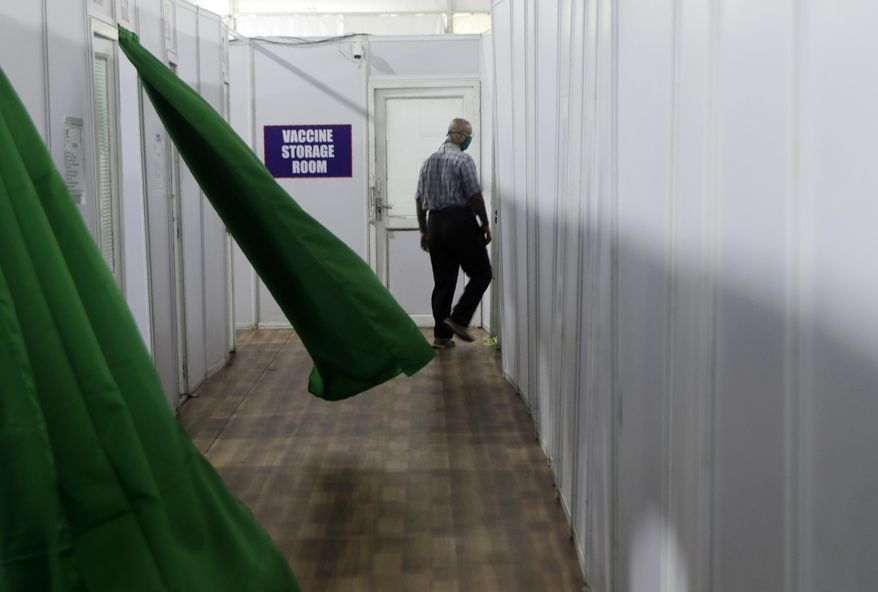 A health worker walks past a storage room during a trial run of COVID-19 vaccine delivery system in Mumbai, India, Friday, Jan. 8, 2021. India tested its COVID-19 vaccine delivery system as it prepares to roll out an inoculation program to stem the coronavirus pandemic. The exercise included necessary data entry into an online platform for monitoring vaccine delivery, along with testing of cold storage and transportation arrangements for the vaccine, according to the health ministry. (AP Photo/Rajanish Kakade)