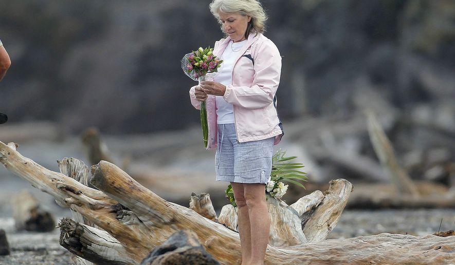 A woman prepares to lay flowers on a beach following a shark attack at Bowentown near Waihi in New Zealand, Friday, Jan 8, 2021. A woman has died Thursday, Jan. 7, in what appears to be New Zealand&#39;s first fatal shark attack in eight years, police say. (George Novak/Bay of Plenty Times via AP)