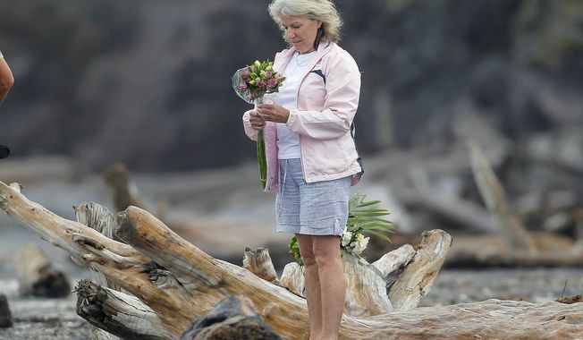 A woman prepares to lay flowers on a beach following a shark attack at Bowentown near Waihi in New Zealand, Friday, Jan 8, 2021. A woman has died Thursday, Jan. 7, in what appears to be New Zealand&#x27;s first fatal shark attack in eight years, police say. (George Novak/Bay of Plenty Times via AP)