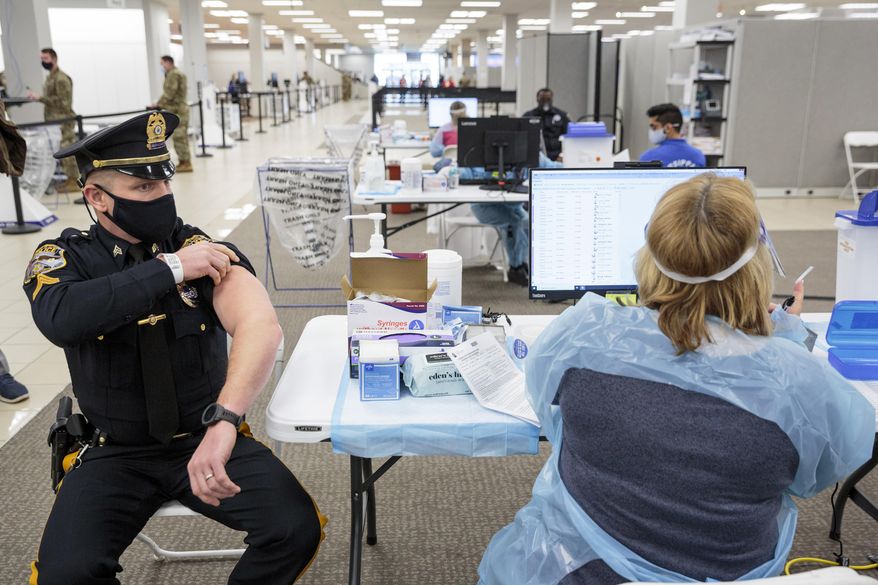 Sergeant Michael Zarro, of the Mount Olive, NJ, Police Department, rolls up his sleeve to receive a COVID-19 vaccination at the Morris County, vaccination site, in Rockaway, NJ, Friday, Jan. 8, 2021. Gov. Phil Murphy toured what's being called a vaccine megasite at a former Sears store in Morris County on Friday where health officials hope to vaccinate more than 2,000 people per day in coming weeks and months. (Sarah Blesener/The New York Times via AP, Pool)