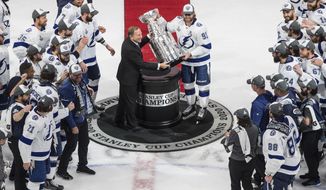 FILE - In this Sept. 28, 2020, file photo, Tampa Bay Lightning&#39;s Steven Stamkos (91) is presented the Stanley Cup from NHL commissioner Gary Bettman as they celebrate after defeating the Dallas Stars in the NHL Stanley Cup hockey finals in Edmonton, Alberta. The NHL is embarking on a 56-game regular season with all divisional play in a knock-down, drag-out battle for the Stanley Cup unlike any other in hockey history.  (Jason Franson/The Canadian Press via AP, File)