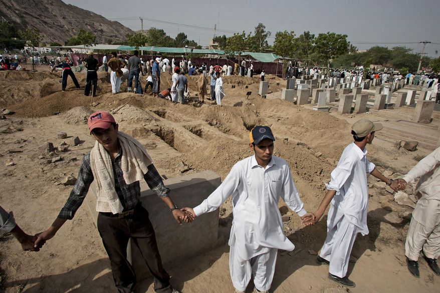 In this May 29, 2010, photo, people from a minority Muslim Ahmadi community stand guard as others prepare to bury the victims of attack by Islamic militants, in Rubwah, some 150 kilometers (93 miles) northwest from Lahore Pakistan. The U.S. Commission on International Religious Freedom on Friday, Jan. 8, 2021, adopted 55-year-old Ramazan Bibi, jailed on blasphemy charges in Pakistan, as a prisoner of conscience. According to a December report by the U.S. Commission for International Religious Freedoms, Pakistan recorded the most cases of blasphemy in the world even though 84 countries have criminal blasphemy laws on their books. (AP Photo/Anjum Naveed) **FILE**