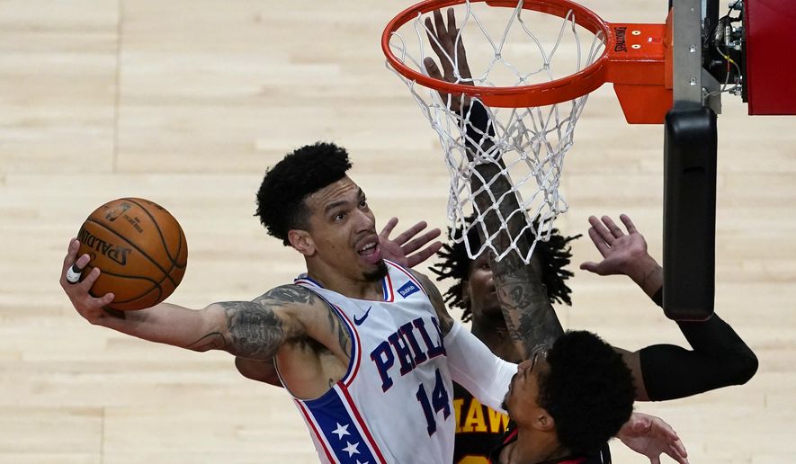 Philadelphia 76ers forward Danny Green (14) goes in for a basket as Atlanta Hawks&#39; John Collins (20), right, and Bruno Fernando (24) defends during the first half of an NBA basketball game Monday, Jan. 11, 2021, in Atlanta. (AP Photo/John Bazemore)